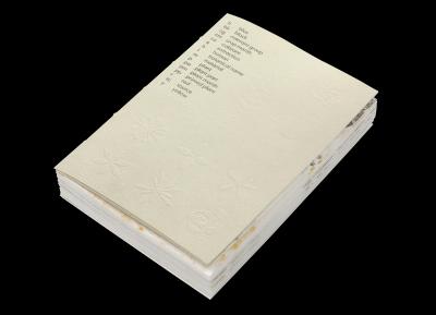 Still life of a research book about sustainable graphic design printed with natural dye plants with embossed plant illustrations.