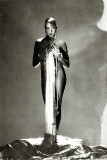 Josephine Baker, standing nude, with a long piece of fabric draped in front of her hanging from long stands of pearls which are wrapped around her hands, 1934. Photographed by George Hoyningen-Huene/Vanity Fair.