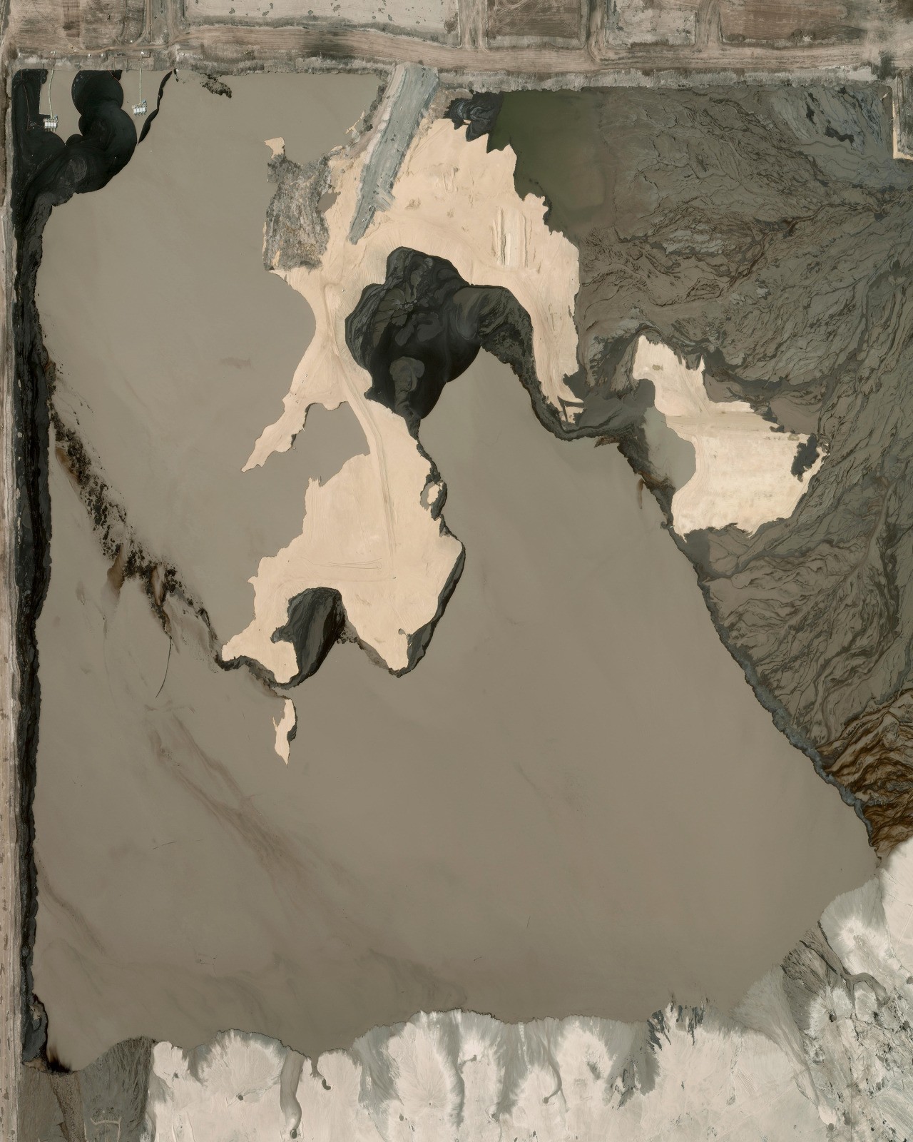 “Waste ponds can be seen at the Athabasca oil sands in Canada. The area contains the largest known deposits of bitumen on Earth. Bitumen is a semi-solid form of crude oil that naturally occurs as a mixture of sand, clay, and water. The additional energy required to mine and then remove the sand from the bitumen leads to the release of more carbon emissions than in any other form of oil production. Extraction takes place by injecting hot water into deep wells so the sands liquefy and can be pumped up to the surface. This waste pond is roughly four square miles (10 square kilometers).”
