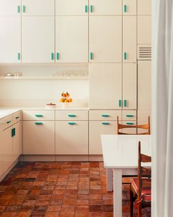 In the kitchen of this Paris apartment, custom lacquered cabinetry is paired with old terra-cotta tiles. Italian designer @f...