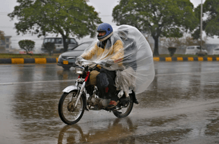 Motorcycle passenger shelters from the wet weather in Islamabad