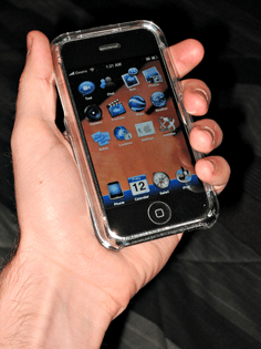 a hand holding an iphone. the phone's wallpaper/background is (likely) a live feed of the camera, making it appear as if the phone were transparent.