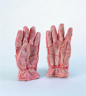Pair of gloves against a white background, the gloves stitched with a red-pink thread, the material looking sausage-like rather than leathery, pink and yellow and purple all over.