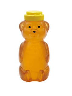 a bottle of honey in the shape of a bear. the lid is yellow and looks like a little yellow hat.