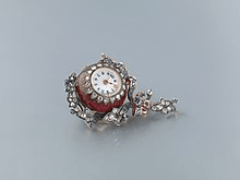 A gold, diamonds and sapphires red guilloché enamel "Boule de Genève", a type of pendant watch used as an accessory for women. An example of an object which is functional, artistic/decorative, marker of social status or a symbol of personal meaning.