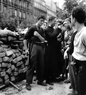 Black and white picture.
 Father Camille Folliet, a French Roman Catholic priest, lends his support and advises the French Resistance behind a barricade during the Battle for Paris