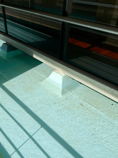 Photo of a water-filled basin, showing lively shadowplay, painted in pale teal, forming the ground floor basement of a large apartment block in Matosinhos, Portugal.