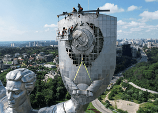 Workers remove a Soviet emblem