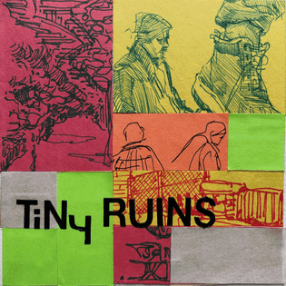 A 5x5 inch collage of various ballpoint and ink pen sketches of people, sights, and signs — all on strips of yellow, red, and orange paper. bright green and light brown sticky notes fill the empty space, with the latter covered by a layer of tracing paper. Vinyl letters in the lower left corner read "TiNy RUINS".