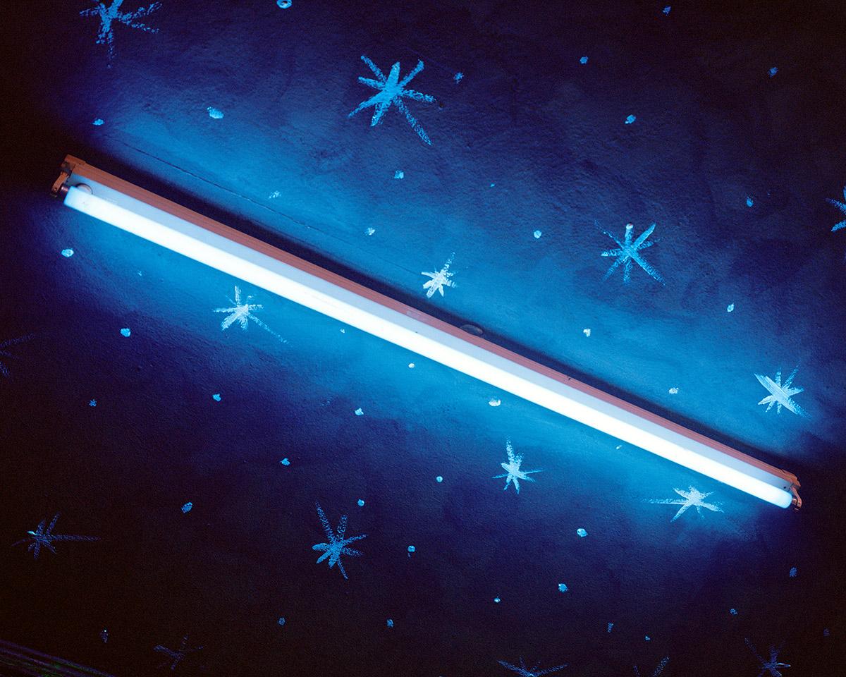 A fluorescent light in a room with stars painted on the ceiling. 