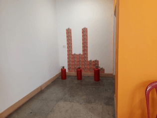 Ascensión de las ánimas benditas. Una instalación en la que sobrepone la imagen del ánima sola generando una estructura de dos torres enfrentada a tres extintores vacíos. 