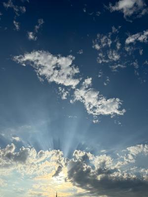 A photo of a blue sky with some clouds and rays of sun