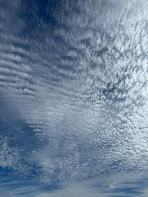A photo of a blue sky with some clouds and rays of sun