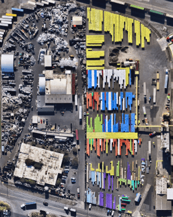 “Brightly colored shipping containers are stacked next to a scrap metal storage yard at the Port of Tacoma, Washington.”