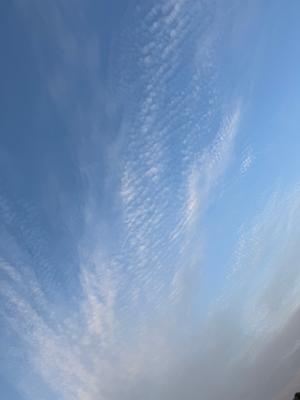 A photo of a blue sky with some clouds and rays of sun